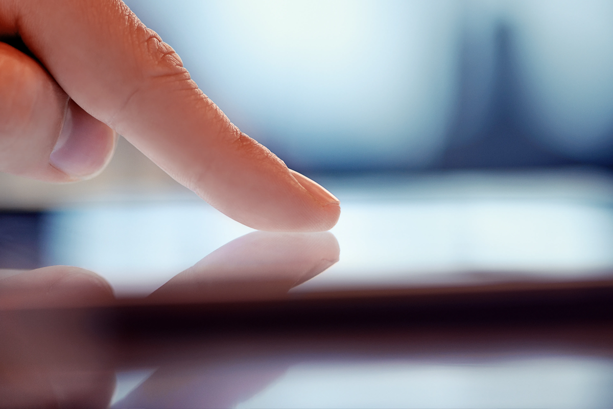 Close-up van een menselijke vinger die een digitaal scherm aanraakt
