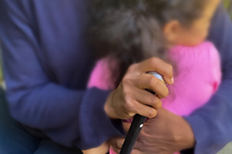 Close-up van oudere vrouw met wandelstok die jong meisje knuffelt