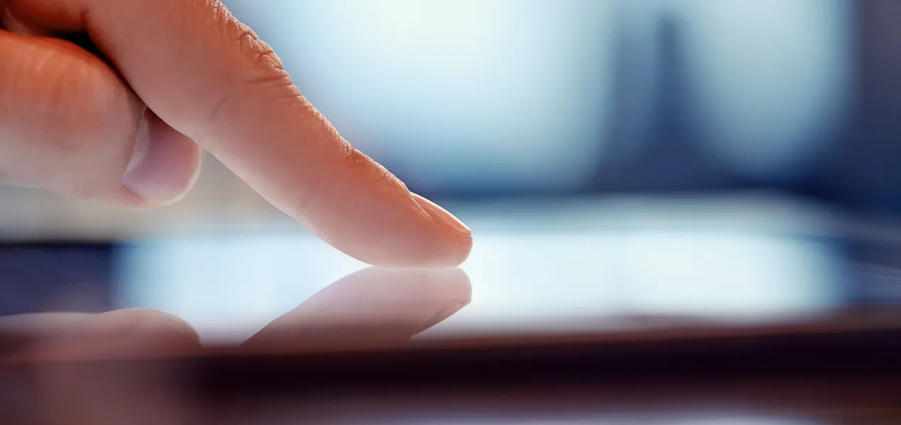 Close-up van een menselijke vinger die een digitaal scherm aanraakt