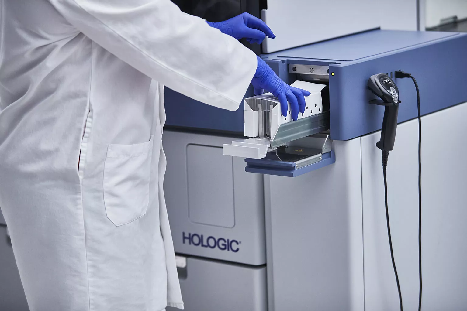 Laborant plaatst lade met buisjes in het Panther-systeem in een laboratorium.