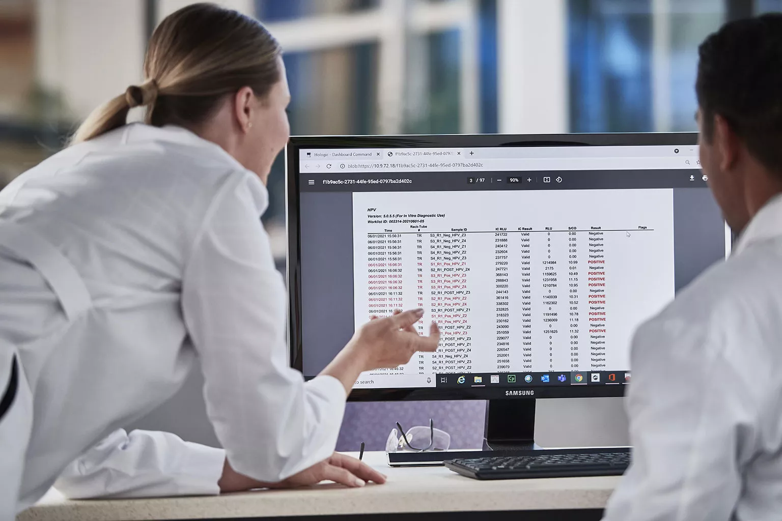 afbeelding van laboranten die gegevens bekijken op een monitor in een laboratorium.