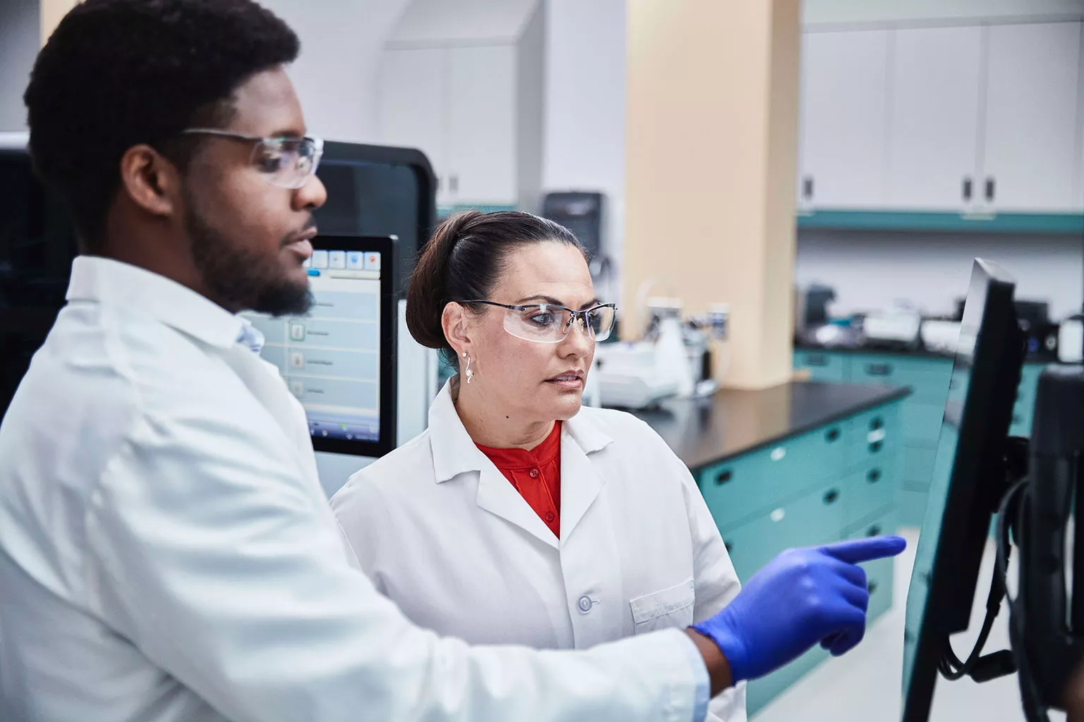 Laborant kijkt en wijst naar beeldscherm in laboratorium