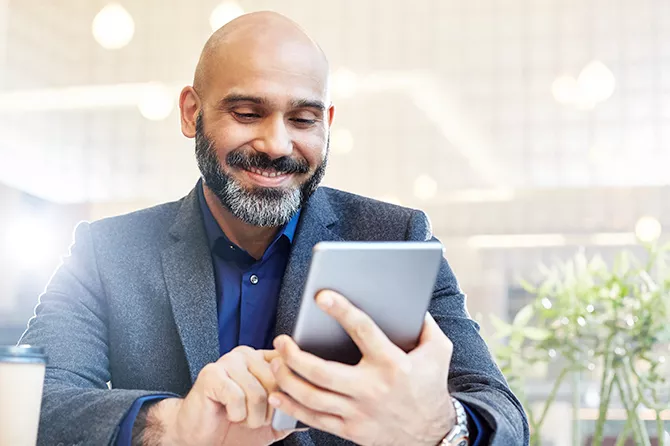 Man glimlacht tijdens interactie met een tablet in een buitenomgeving