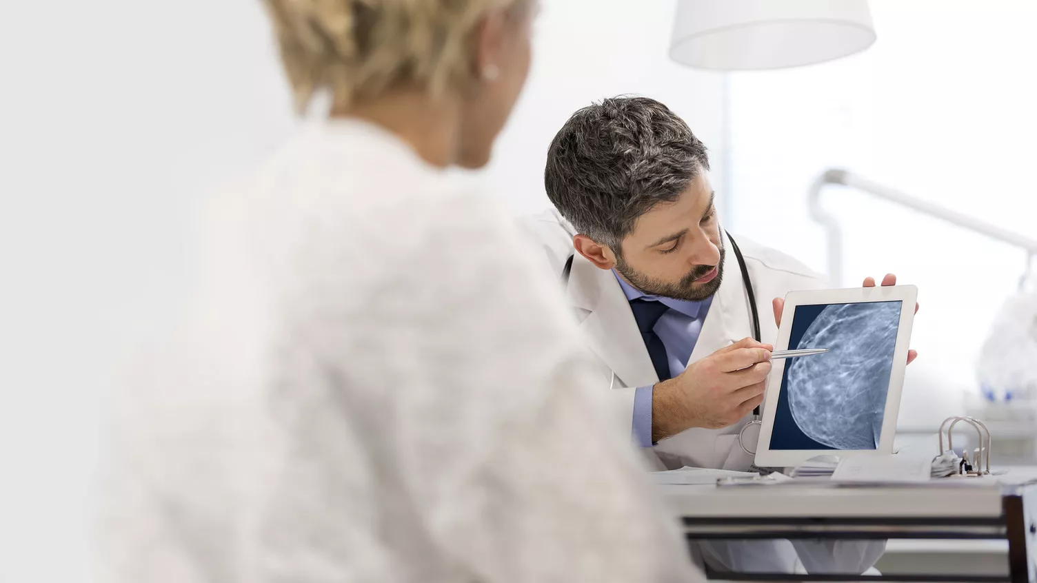 Klinisch laborant wijst naar apparaat om borstscan te laten zien