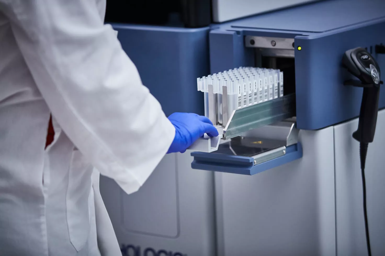 Laboratoriumtechnicus duwt tray met flacons in medisch systeem